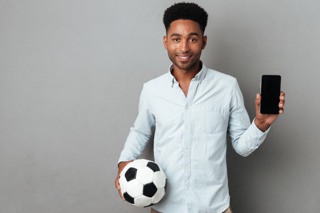 Jeune homme avec un ballon de football et un smartphone 